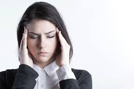 Woman holding her temples with a pained expression, suggesting she is experiencing a headache or migraine.